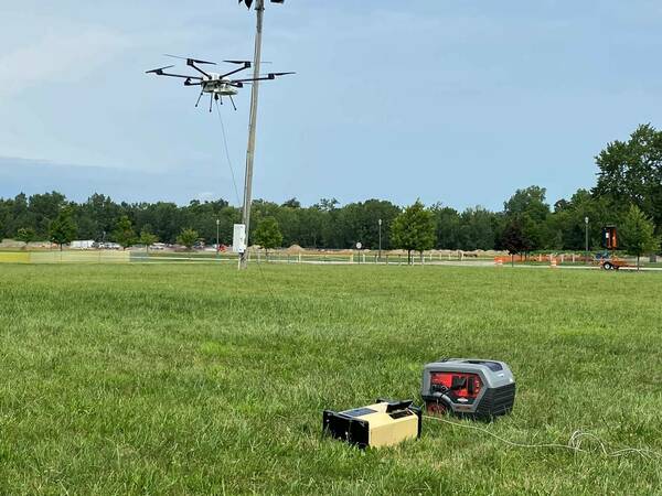 Orion 2.2 six-rotor tethered drone in flight above a grassy field