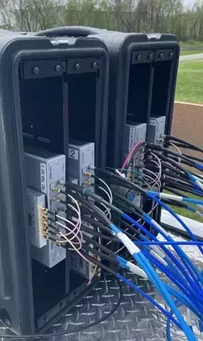 16 channel receiver consisting of two black cases with 4 Ettus N310s mounted inside. Multiple blue and black wires are connected to the N310 units.